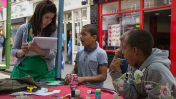 A woman interviewing children at a market