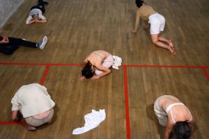 five people lie on a school gym floor