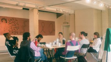 photograph of artists sitting around a table talking