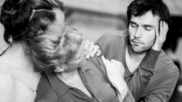 Three dancers lean in a close embrace