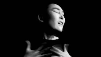 A person silouhetted against a black background, fingers outstretched and in motion