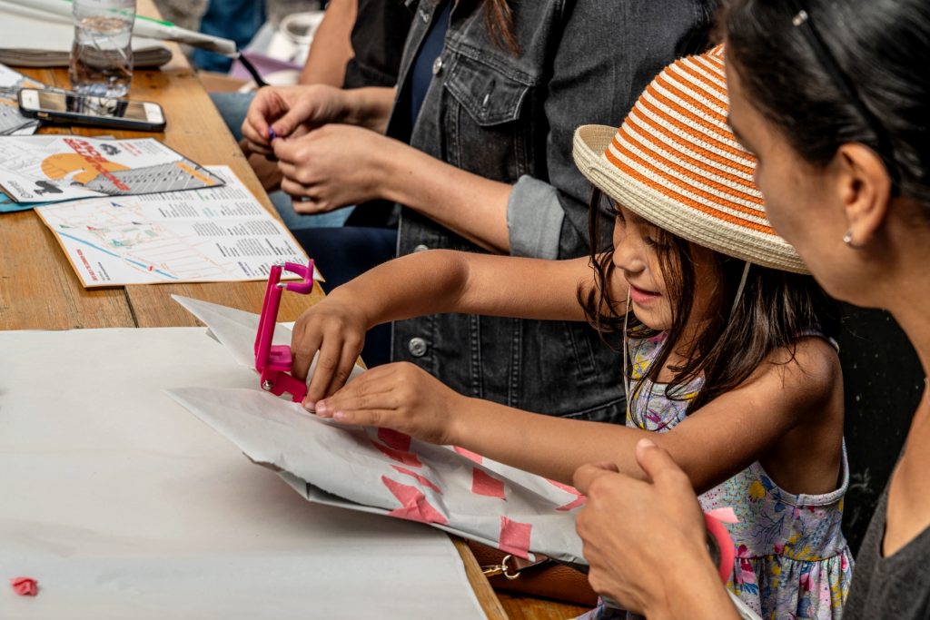 a young girl smiling and making something out of paper
