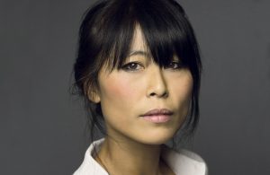 A photo of an East Asian woman. She has dark hair which is tied up, and a fringe which reaches her brown eyes